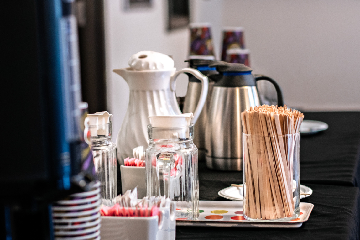 Breakroom - 72 dpi A table set up filled with Milk, Coffee and Tea Jugs along with sugar packets, stir sticks and reusable coffee cups all provided by Bruhub Office Coffee Services
